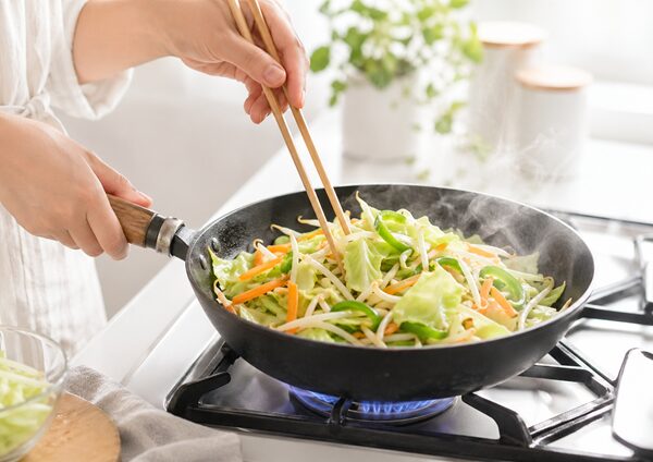 フライパンで色とりどりの野菜をさっと炒めている手元の様子