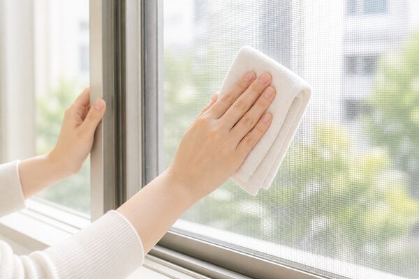 外せない網戸を室内側からクロスでやさしく拭いている写真風画像