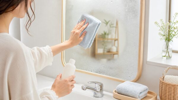 曇った鏡をクロスでやさしく拭きながら曇り止め対策をするイメージ